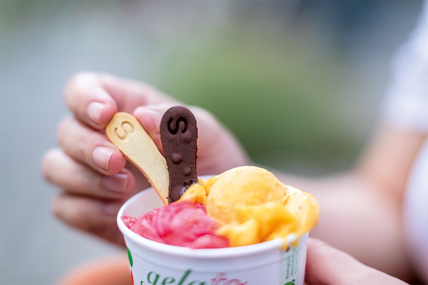 Zwei Kugeln Eis in einem Becher mit zwei kleinen Löffeln.