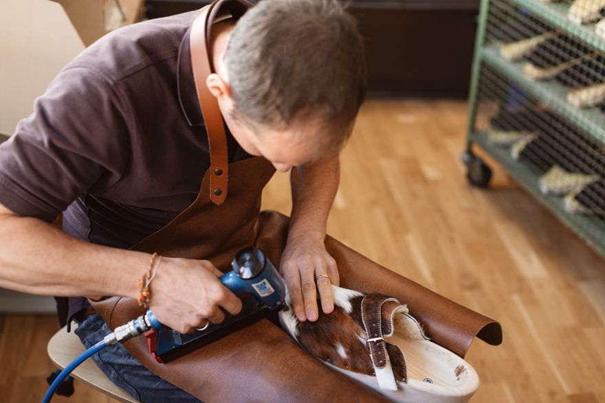 Person bearbeitet ein Schuh aus Leder in einer Werkstatt.