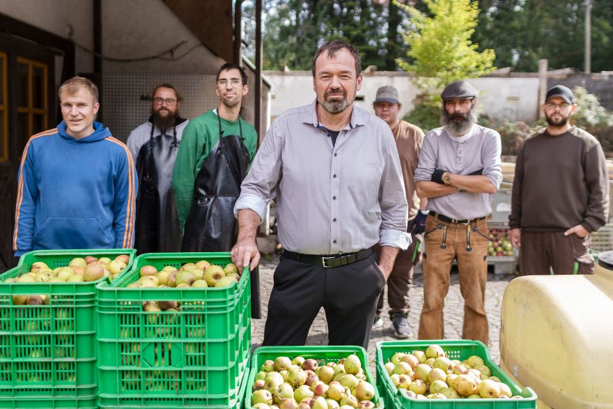 Mehrere Personen stehen im Freien hinter grünen Kisten mit Obst.