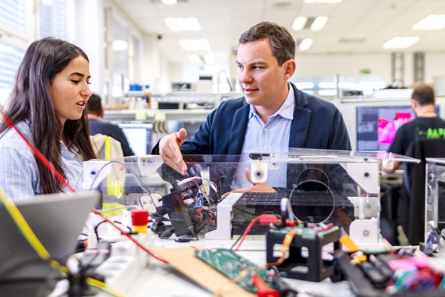 Zwei Personen untersuchen gemeinsam ein technisches Gerät mit elektronischen Bauteilen.