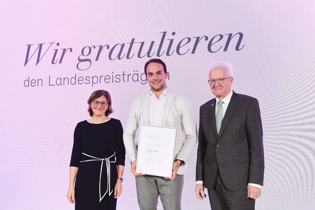 Edith Weymayr und Winfried Kretschmann mit Landespreis-Preisträger auf der Bühne.