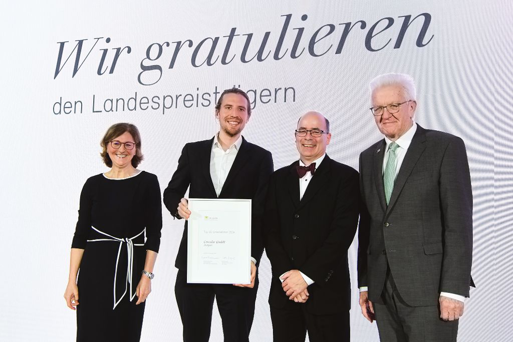 Edith Weymayr und Winfried Kretschmann mit Landespreis-Preisträger auf der Bühne.