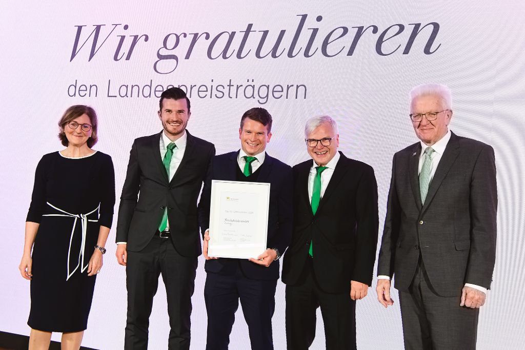 Edith Weymayr und Winfried Kretschmann mit Landespreis-Preisträger auf der Bühne.