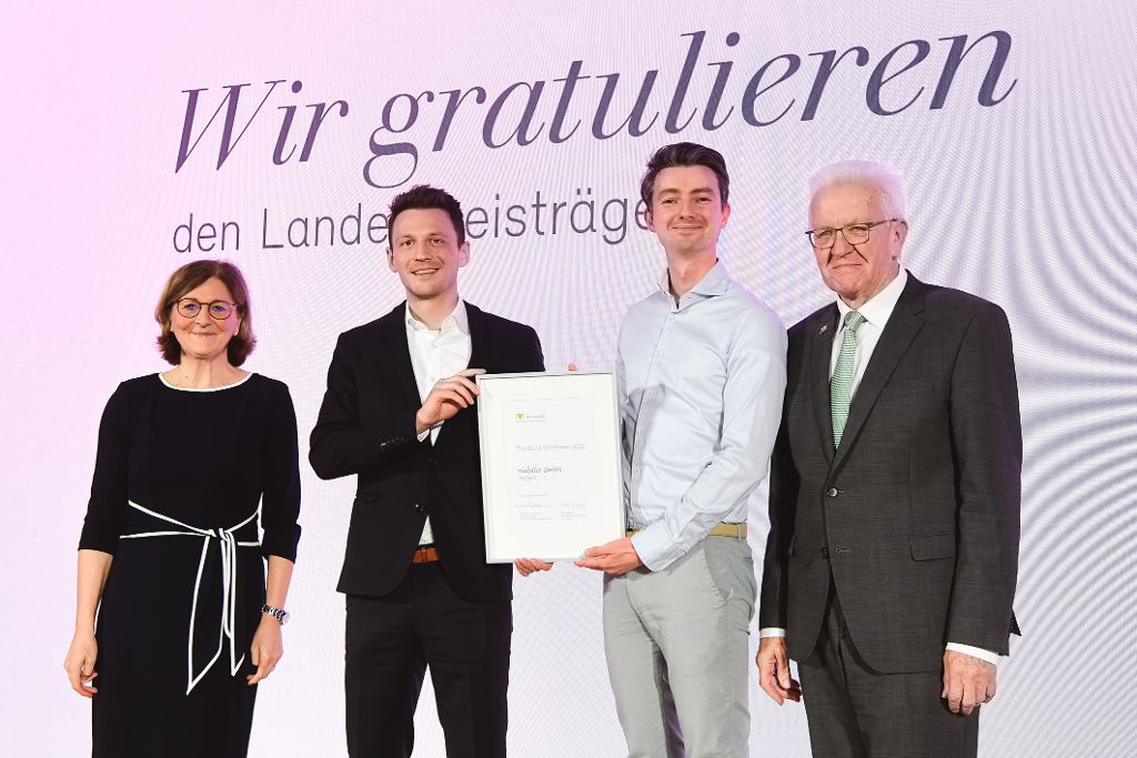 Edith Weymayr und Winfried Kretschmann mit Landespreis-Preisträger auf der Bühne.