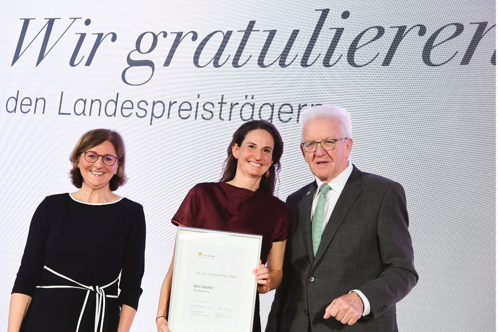 Edith Weymayr und Winfried Kretschmann mit Landespreis-Preisträger auf der Bühne.