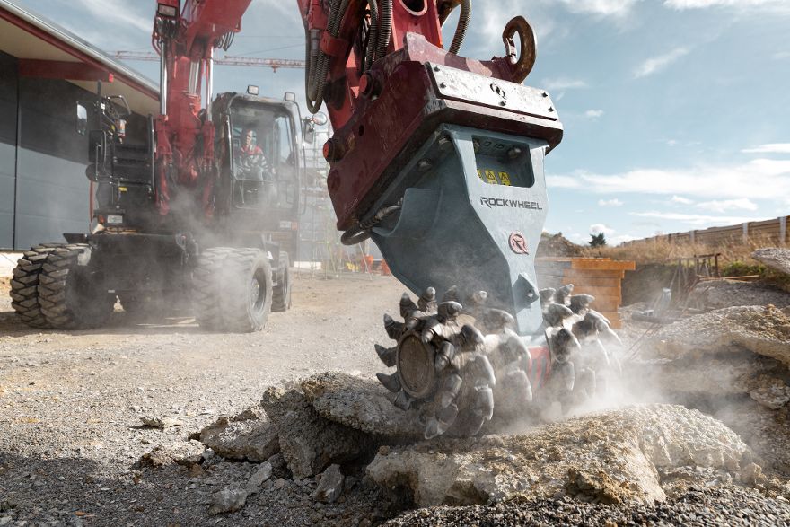Große Baumaschine zerkleinert Beton oder Gestein auf einer Baustelle. Dabei entstehen Staub und Schutt.
