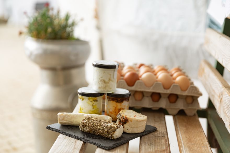 Regionale Lebensmittel wie Eier, Käse und Aufstriche auf einer Holzbank präsentiert.